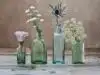 three green and one blue glass vases with flowers inside